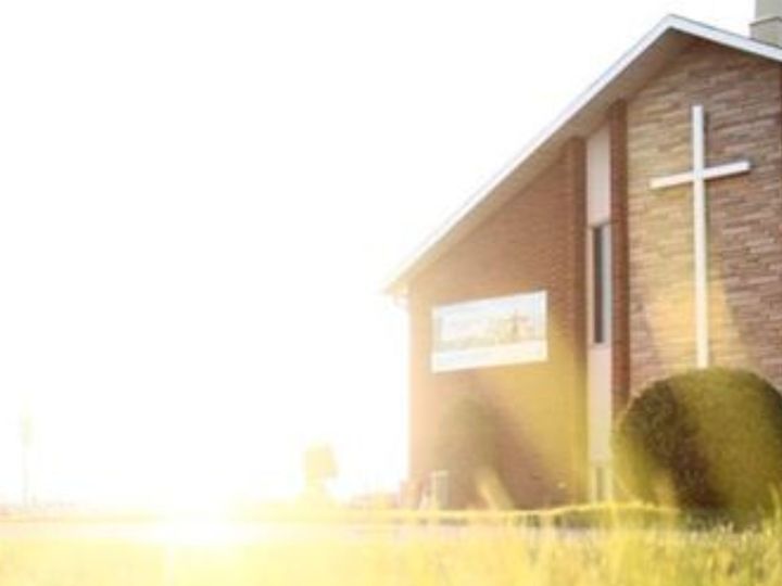 A local church building with a cross, in morning light